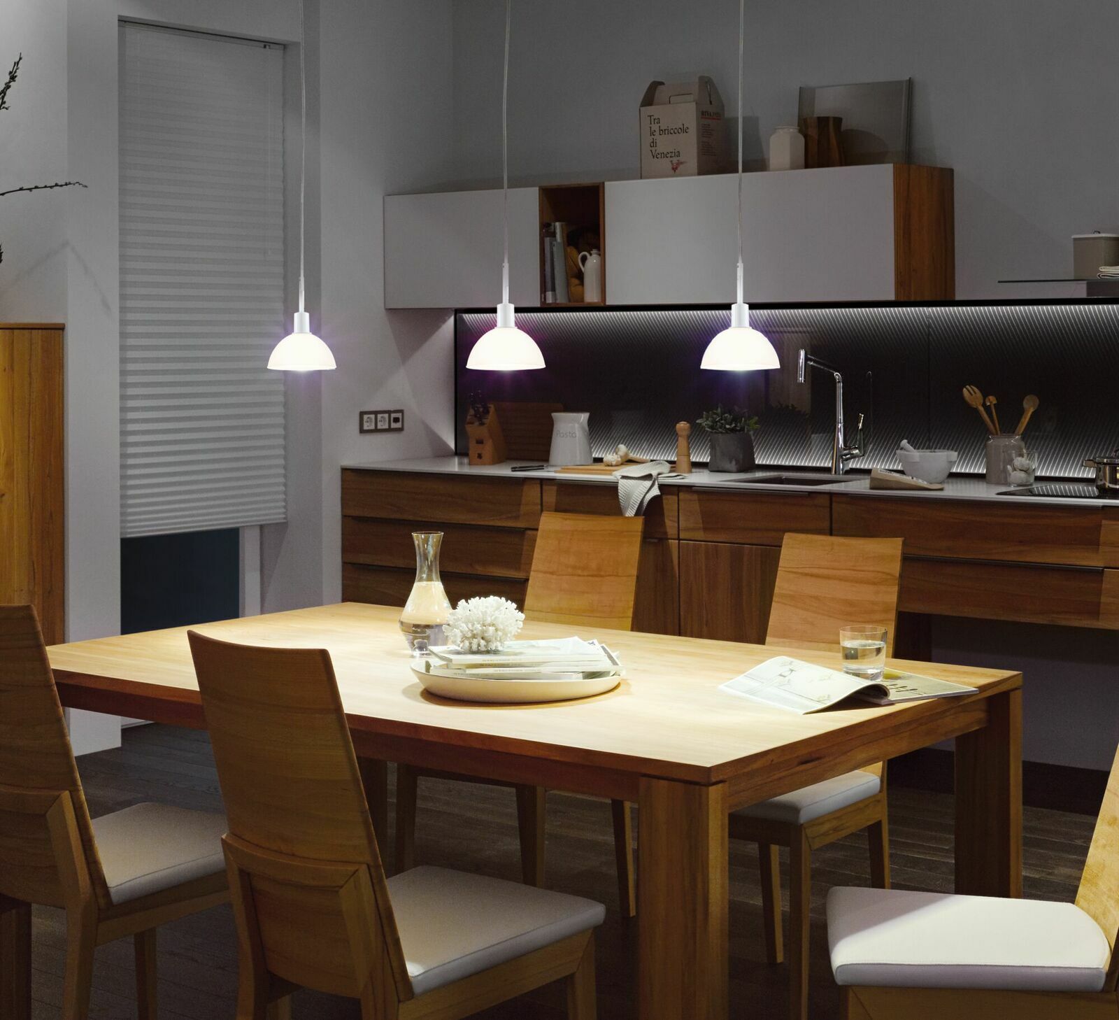 Moderne Pendelleuchten über einem Esstisch in einer stilvollen Küche, seitliche Perspektive.