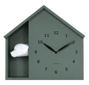 Grüne Wanduhr in Form eines Hauses mit schwarzem Zifferblatt und einem weißen Hundekopf auf der linken Seite, Frontalansicht