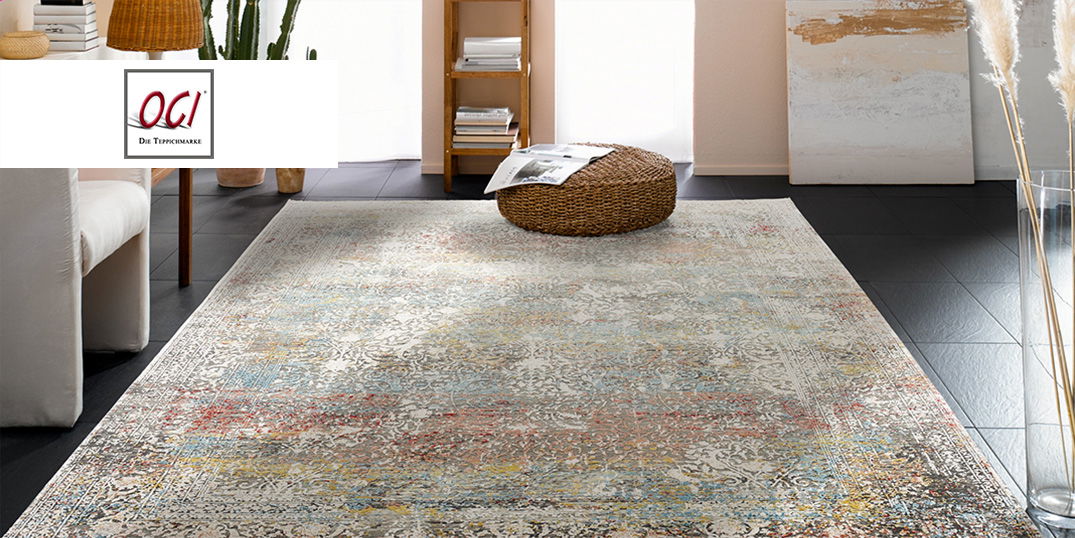 Ein farbenfroher, gemusterter Teppich in einem hellen Wohnzimmer mit einem weißen Sessel, einem Bücherregal auf einem schwarzen Fliesenboden.