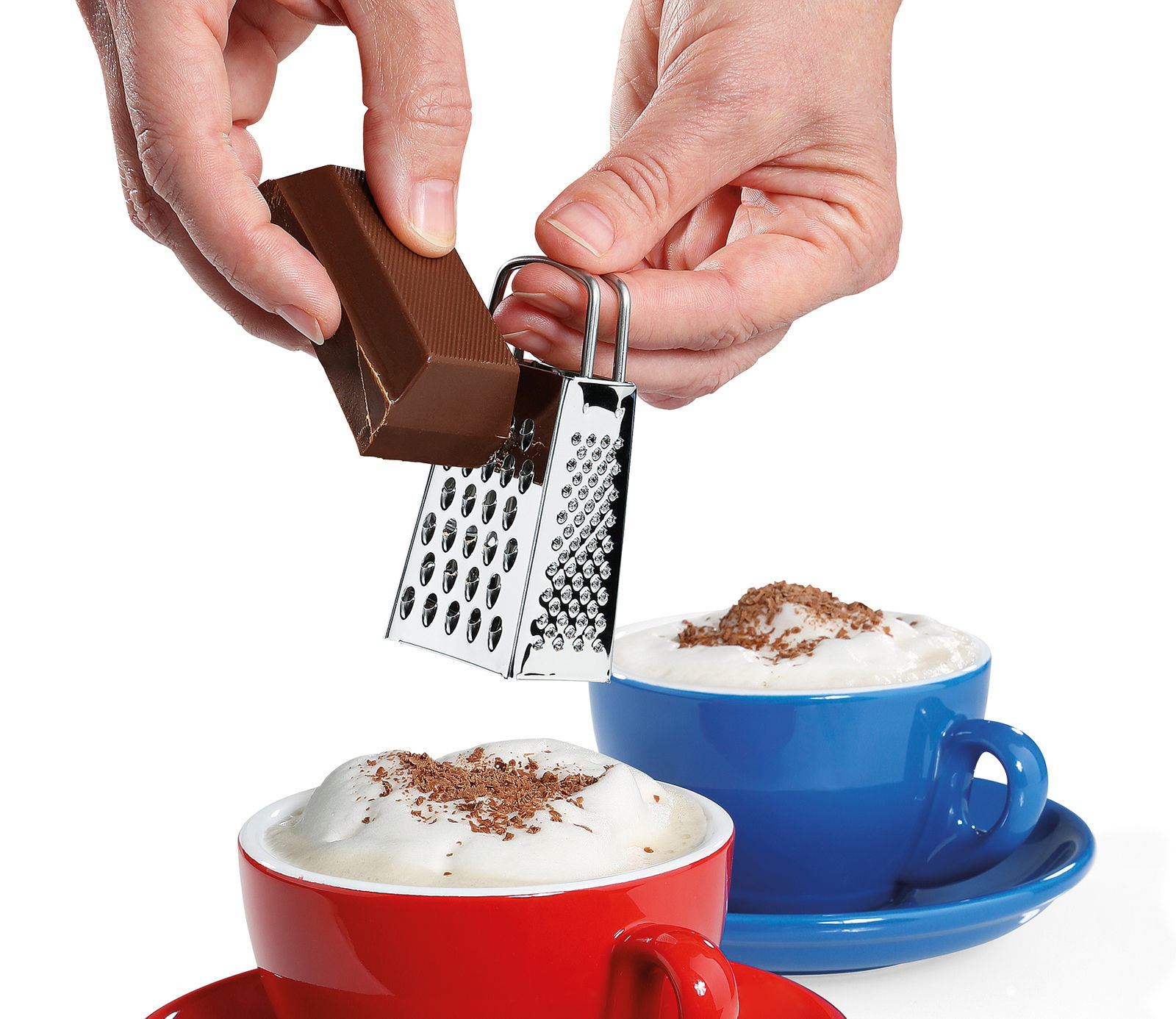 Mini-Vierkantreibe in der Hand, die Schokolade über einer Tasse mit Milchschaum reibt, seitliche Perspektive.