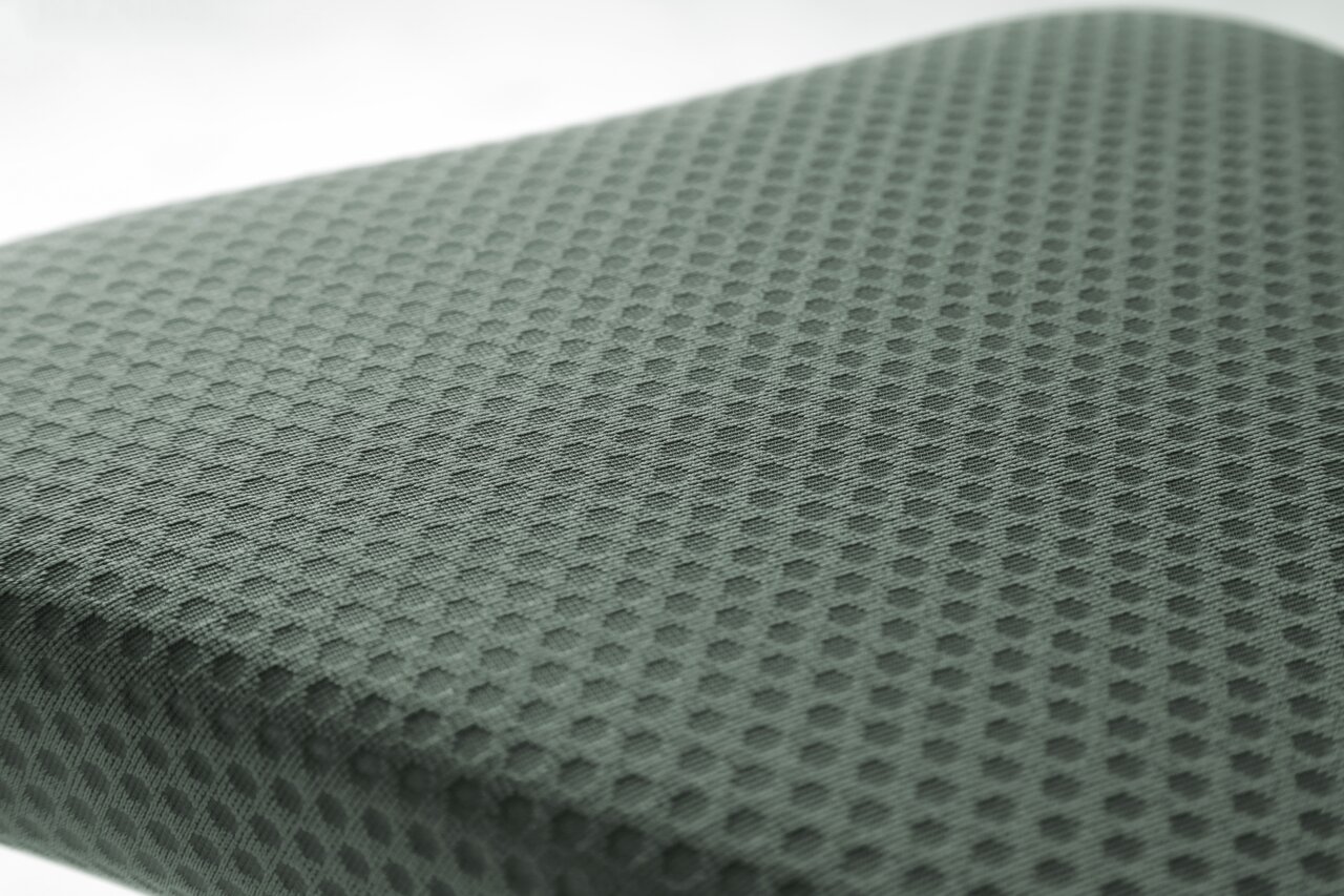 Close-up van een gestoffeerde stoel met honingraatpatroon, vanuit een perspectief van bovenaf gefotografeerd.