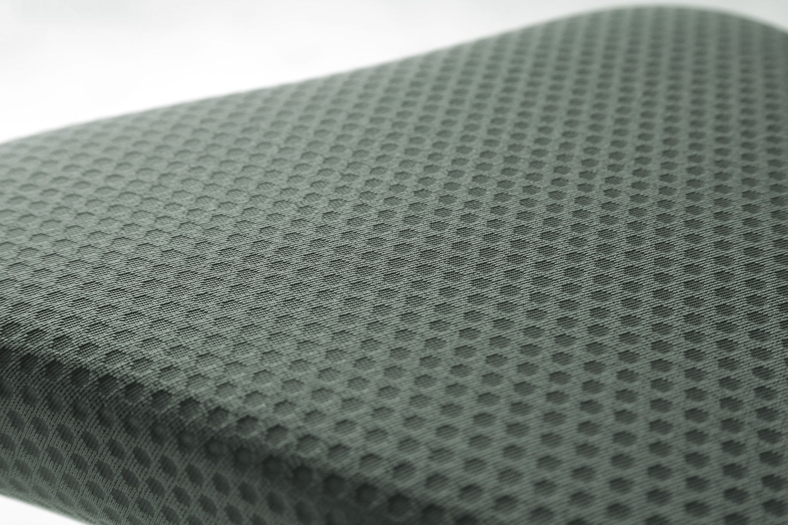 Nahaufnahme eines gepolsterten Sitzes mit wabenförmigem Muster, perspektivisch von oben fotografiert.