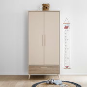 Moderner Kleiderschrank mit zwei Türen und einer Schublade in hellem Holzdesign, frontal fotografiert. Dekoriert mit einem Korb und einem Stofftier auf der Oberseite.