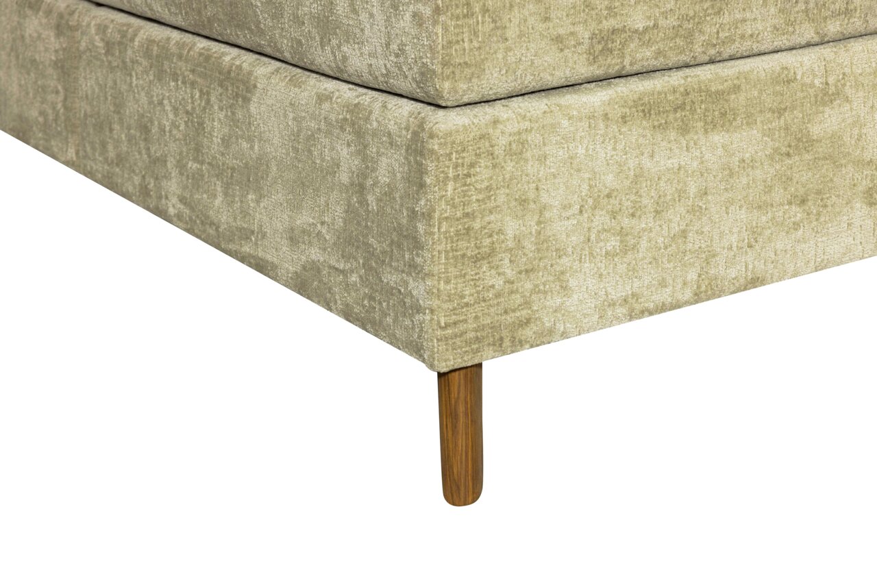 Nahaufnahme eines Boxspringbettes in Beige mit Holzfuß, Perspektive von der Ecke.