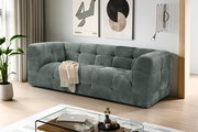 Modernes, gepolstertes 3-Sitzer-Sofa in petrolgrauem Stoff mit Kassettensteppung im Wohnzimmer, schräg von vorne aus leicht erhöhter Perspektive fotografiert