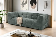 Modernes, gepolstertes 3-Sitzer-Sofa in petrolgrauem Stoff mit Kassettensteppung im Wohnzimmer, schräg von vorne aus leicht erhöhter Perspektive fotografiert
