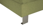 Close-up van een groene zithoek met metalen poten, gezien van onderaf.