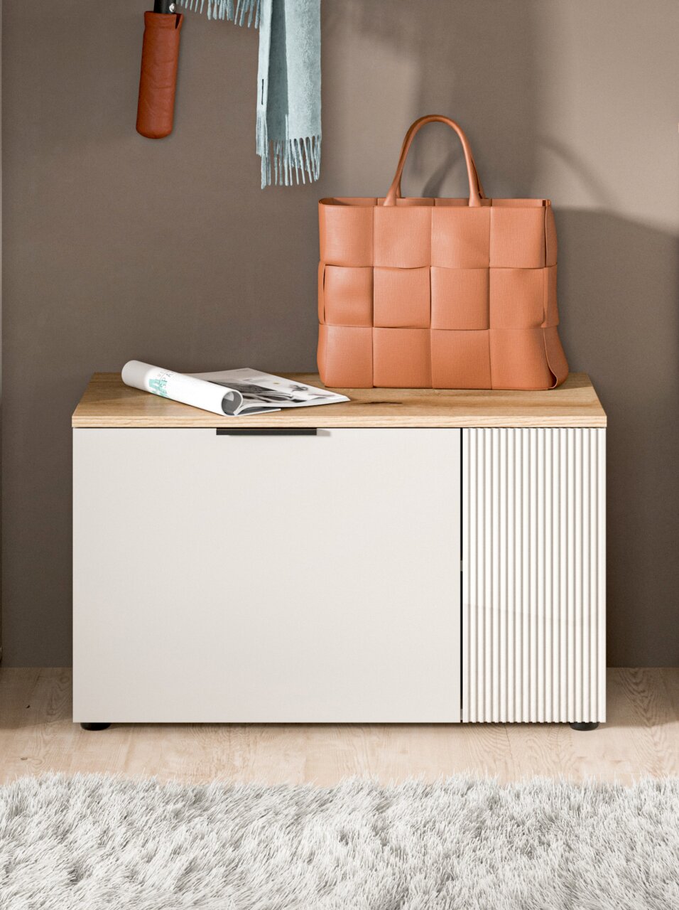 Sitzbank mit Holzoberfläche und weißer Front, darauf eine geflochtene Tasche und eine Zeitung, fotografiert aus frontaler Perspektive.