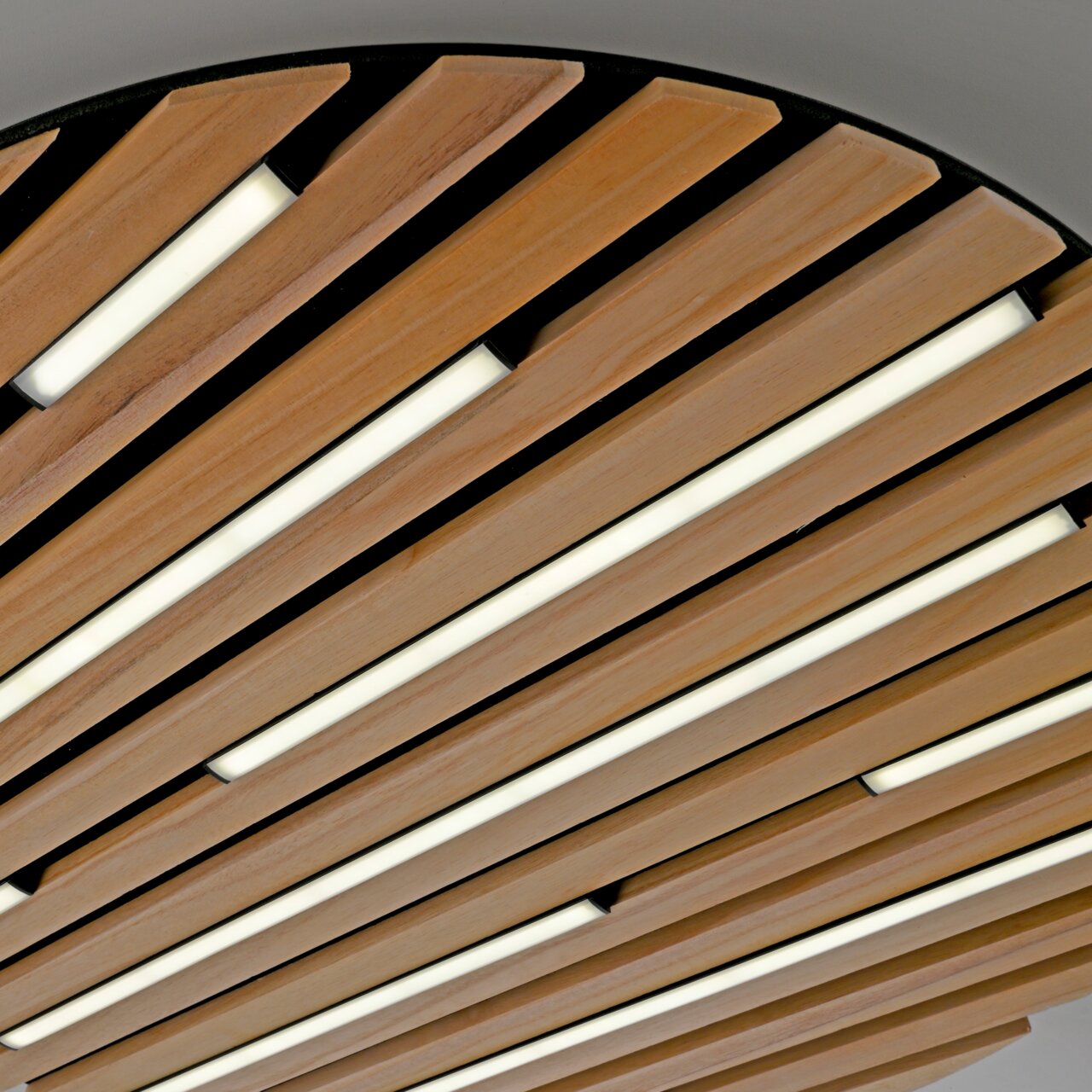 Nahaufnahme der Paul Neuhaus Wand- und Deckenleuchte Q-AKUSTIK mit Holzlamellen und integrierten LED-Lichtstreifen, von unten betrachtet.