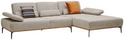 Beige Longchairkombination mit zwei dekorativen Kissen, eines mit Muster und eines in Orange, von schräg vorne betrachtet.
