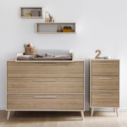 Breite Kommode aus Holz mit Wickelauflage, frontal fotografiert, daneben ein schmaler Schrank mit drei Schubladen.