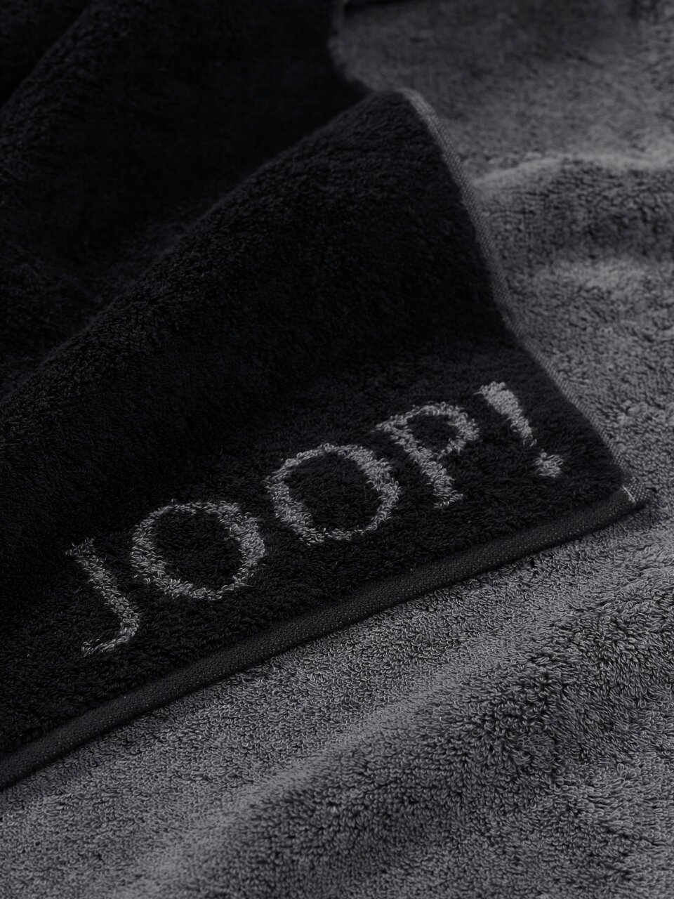JOOP! Saunatuch 80x200 DOUBLEFACE CLASSIC Nahaufnahme eines grauen Saunatuchs mit schwarzem Rand und dem Schriftzug 'JOOP!'