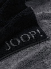 Nahaufnahme eines grauen Saunatuchs mit schwarzem Rand und dem Schriftzug 'JOOP!'
