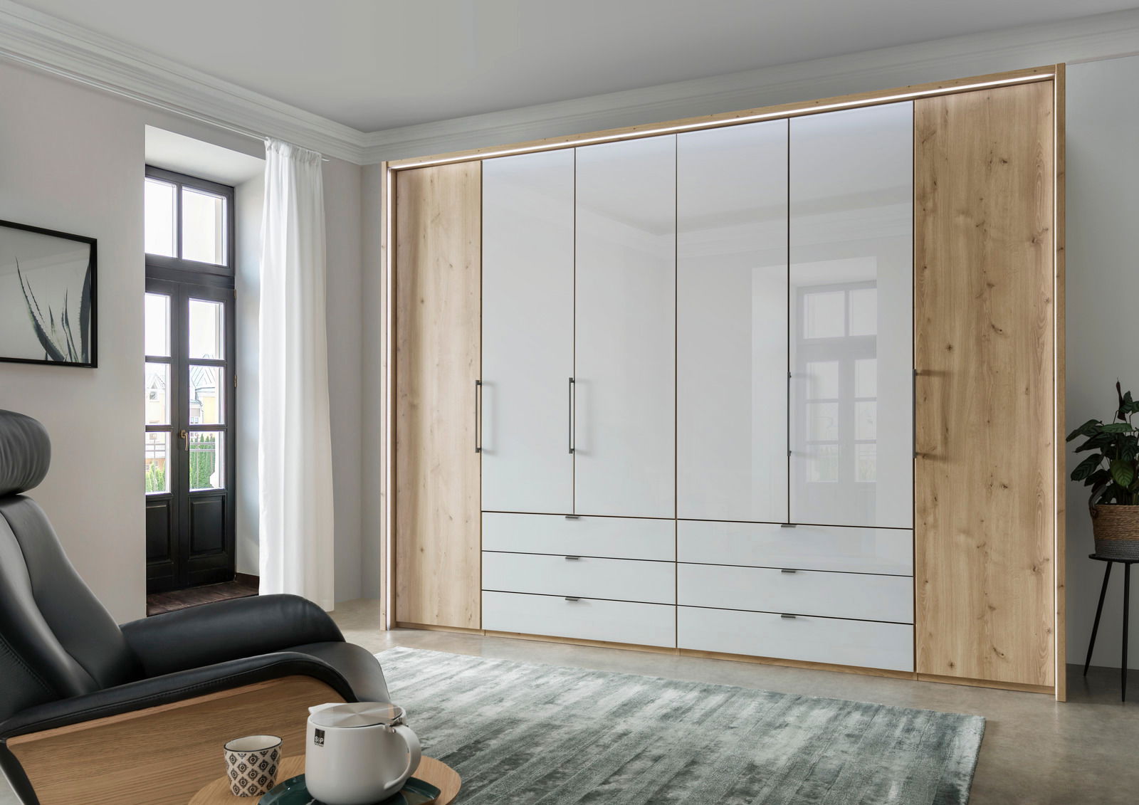 Moderner 6-türiger Falttürenschrank in Holzoptik mit weißen Fronten, frontal fotografiert in einem stilvoll eingerichteten Raum.