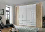 Moderner 6-türiger Falttürenschrank in Holzoptik mit weißen Fronten, frontal fotografiert in einem stilvoll eingerichteten Raum.