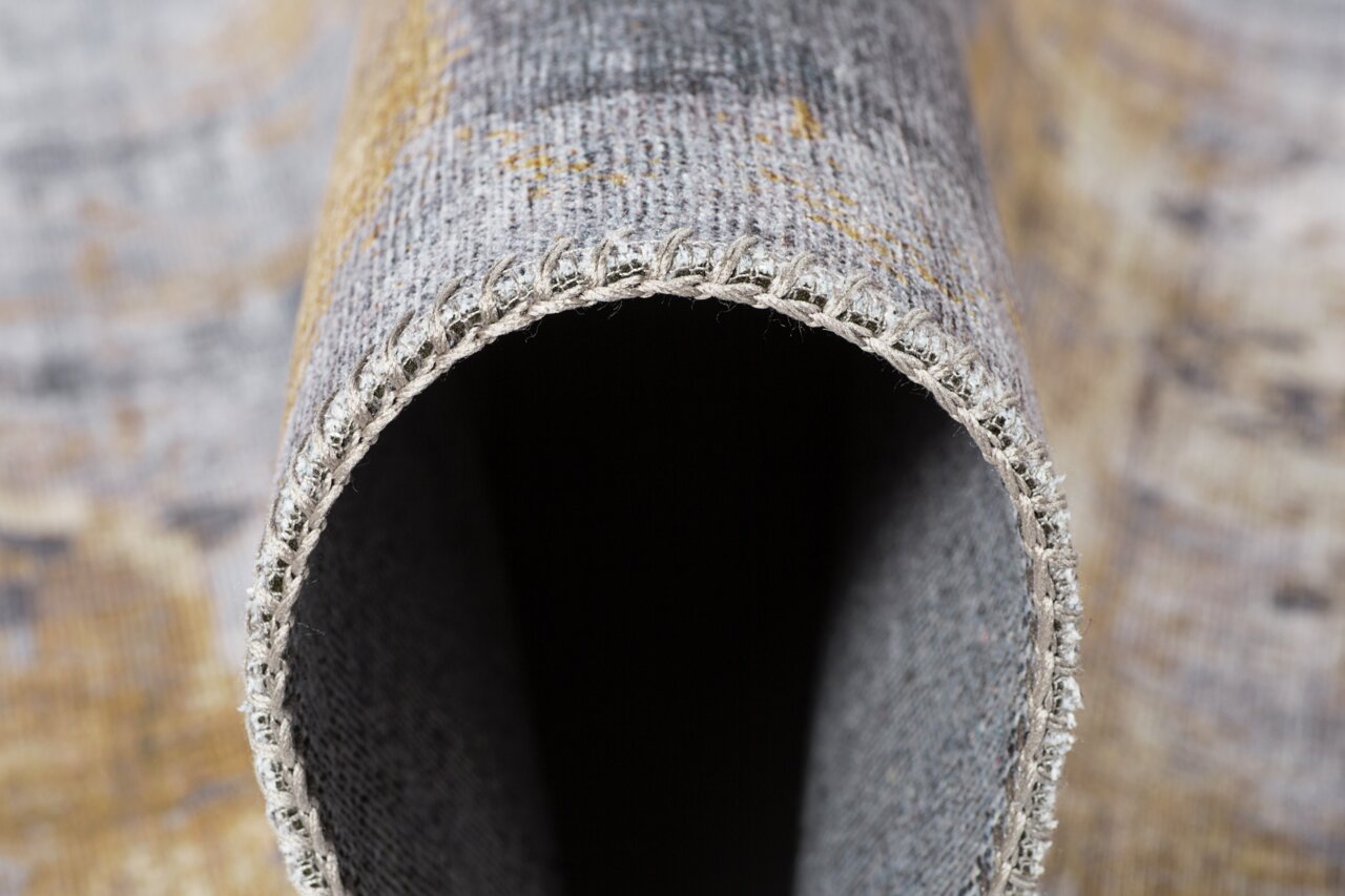 Nahaufnahme eines gerollten Teppichs mit sichtbarer Kante und Textur, Perspektive von der Seite