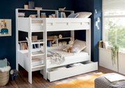 Een wit stapelbed met ingebouwde planken, versierd met speelgoed en boeken, in een lichte kinderkamer met uitzicht op het raam.