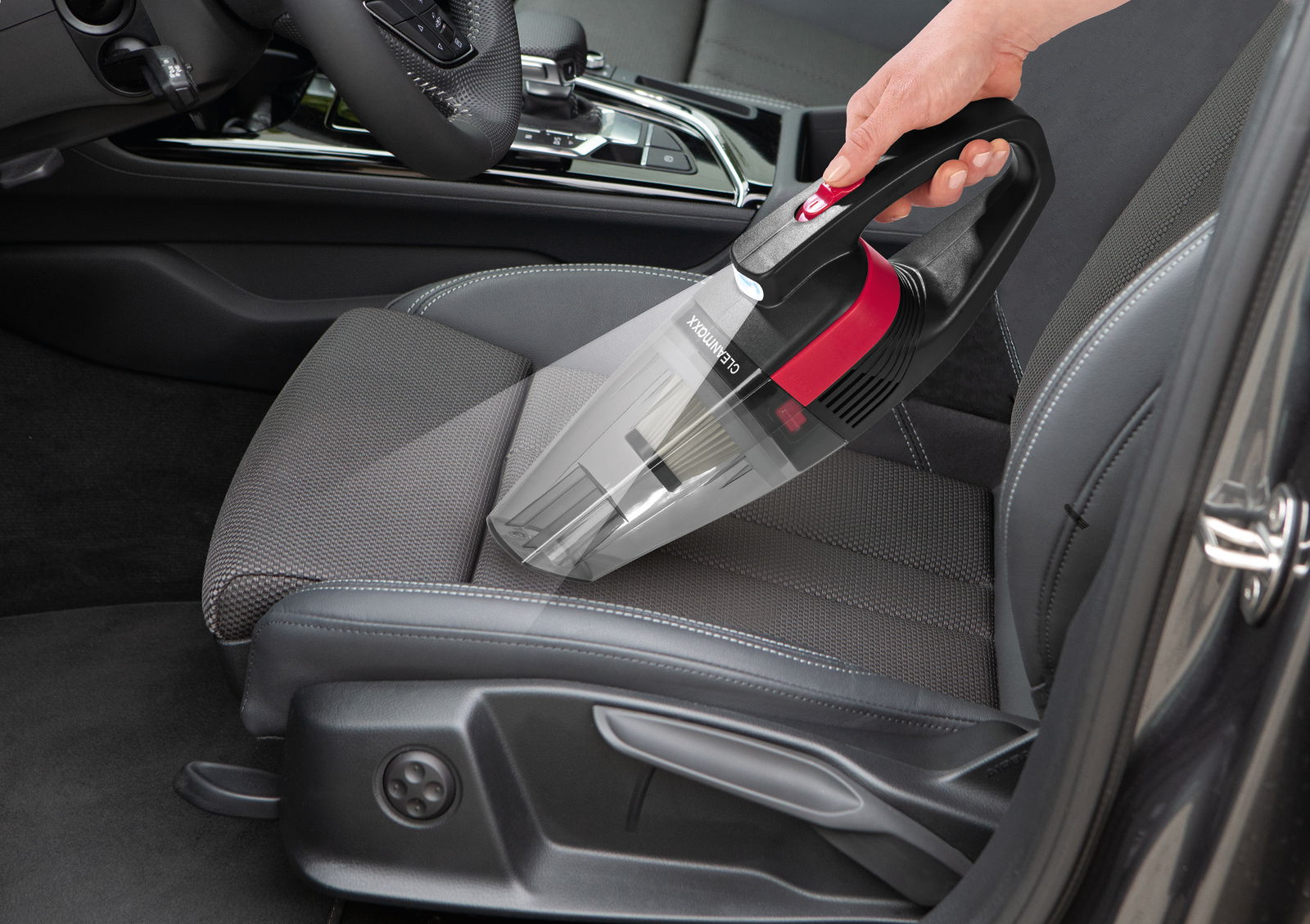 Akku Handstaubsauger in der Hand, der auf einem Autositz verwendet wird, seitliche Perspektive