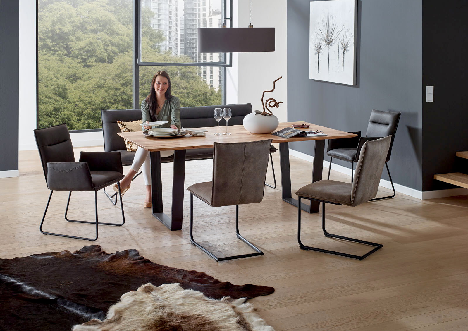 Valnatura Esstisch SCALA Moderner Esstisch mit Holzplatte und schwarzen Metallbeinen, umgeben von stilvollen Stühlen in einem hellen Raum mit großen Fenstern, seitliche Perspektive.