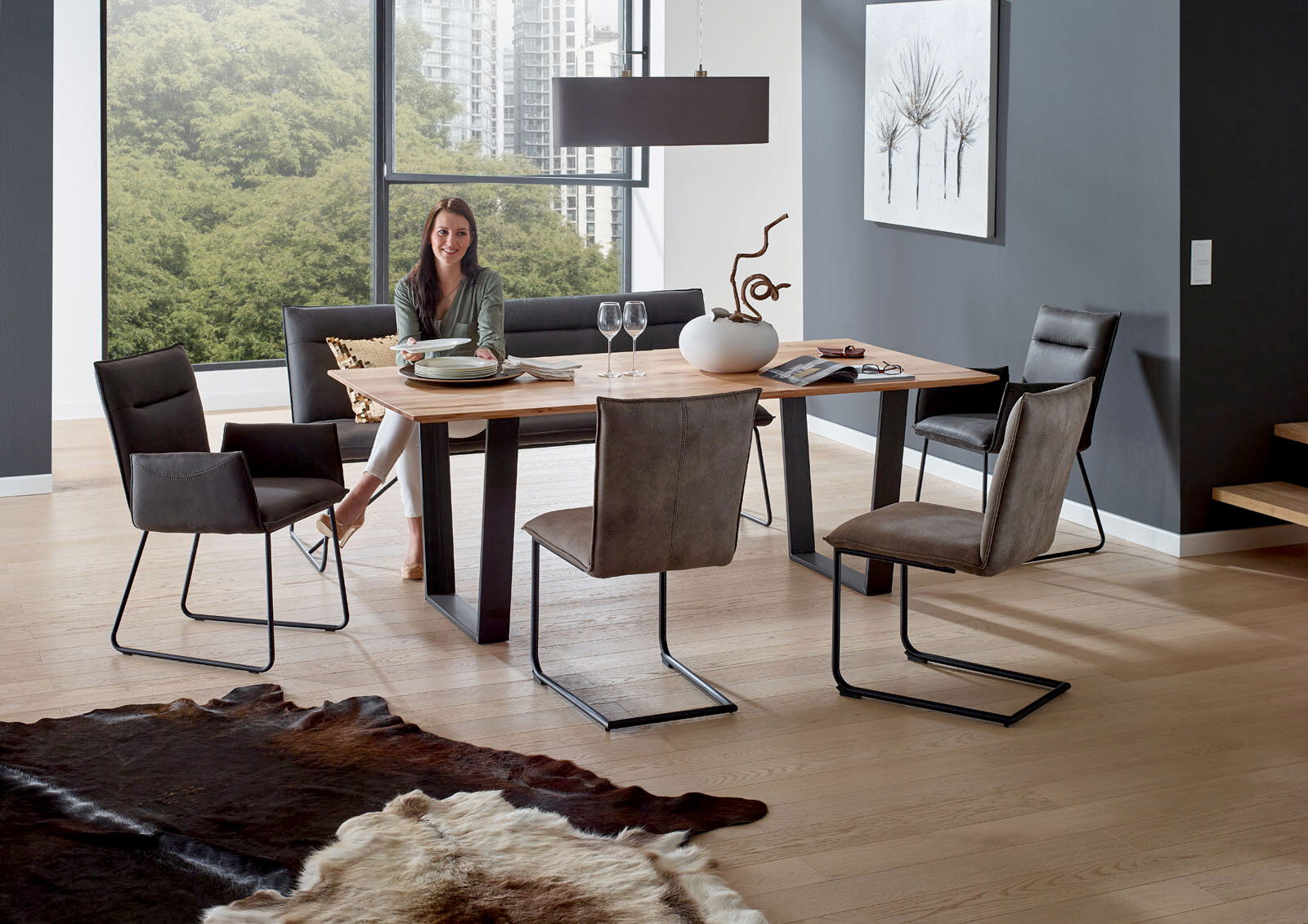 Valnatura Esstisch SCALA Moderner Esstisch mit Holzplatte und schwarzen Metallbeinen, umgeben von stilvollen Stühlen in einem hellen Raum mit großen Fenstern, seitliche Perspektive.