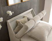 Nahaufnahme eines eleganten Boxspringbetts mit beigen Kissen und einem gepolsterten Kopfteil, seitliche Perspektive.