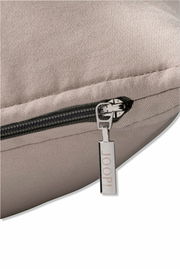 Nahaufnahme einer beigen Zierkissenhülle mit Reißverschluss und einem Anhänger mit der Aufschrift 'JOOP!'