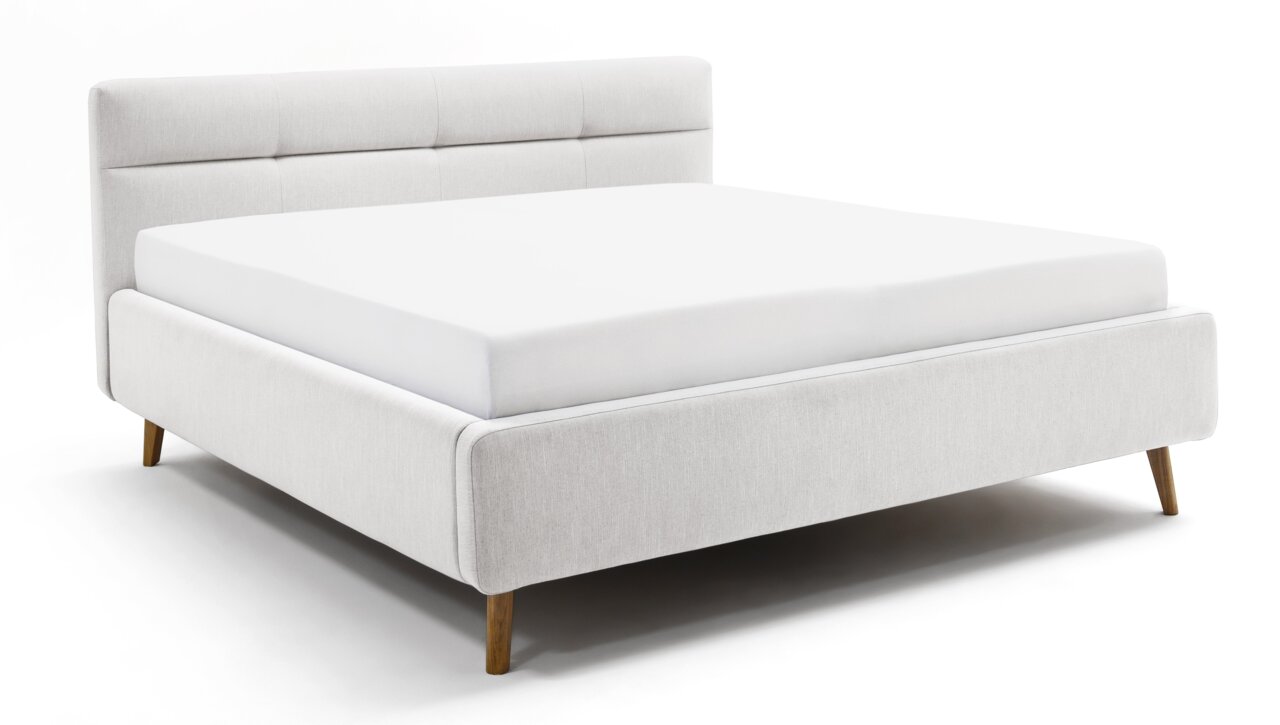 Modern gestoffeerd bed van lichte stof met houten poten, zijaanzicht