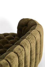 Nahaufnahme einer olivgrünen Couch mit gestepptem Design und weicher Polsterung, seitliche Perspektive.