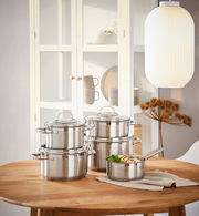 Elegantes 5-teiliges Topfset aus Edelstahl auf einem Holztisch, seitliche Perspektive.