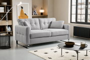 Modernes hellgraues 2-Sitzer-Sofa mit gesteppter Rückenlehne, breiten Armlehnen und verchromten Kufenfüßen im Wohnzimmer, schräg von vorne links fotografiert