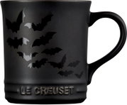 Schwarzer Le Creuset Becher mit glänzendem Fledermausmotiv und erhabenem Markenlogo, frontal mit rechts sichtbarem Henkel dargestellt