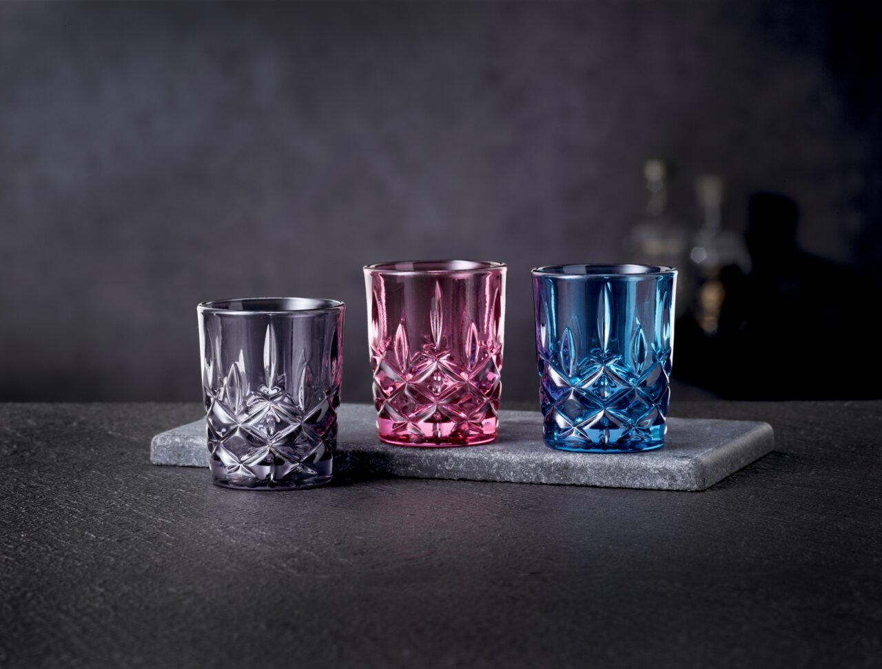 Nachtmann Stampler-Set 3 tlg. NOBLESSE Drei bunte Stamper-Gläser in Lila, Pink und Blau auf einer grauen Steinplatte, seitliche Perspektive.