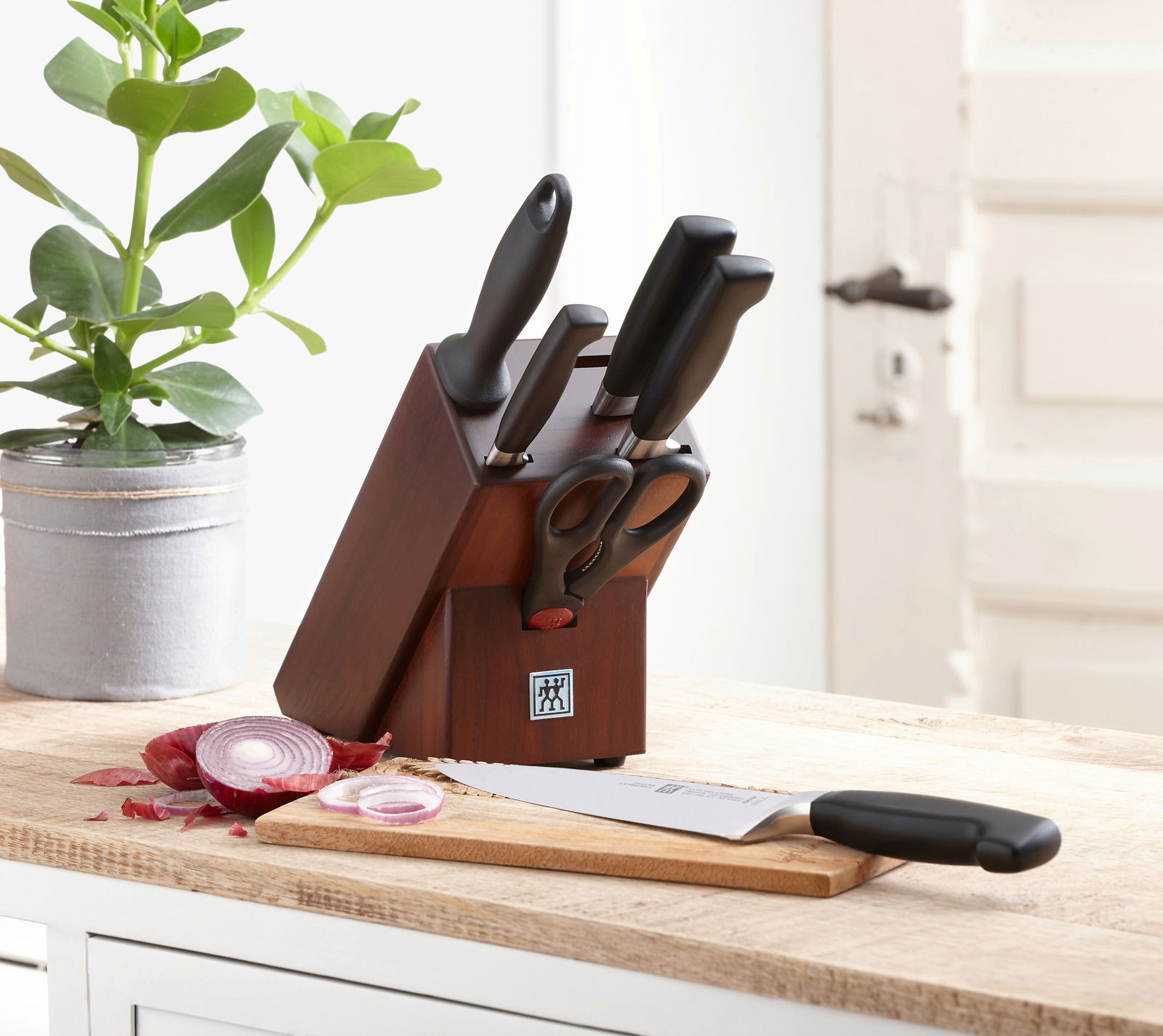 Messerblock aus Walnussholz mit mehreren Messern und einer Schere, auf einer Küchenarbeitsplatte platziert, seitliche Perspektive.