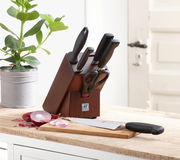 Messerblock aus Walnussholz mit mehreren Messern und einer Schere, auf einer Küchenarbeitsplatte platziert, seitliche Perspektive.