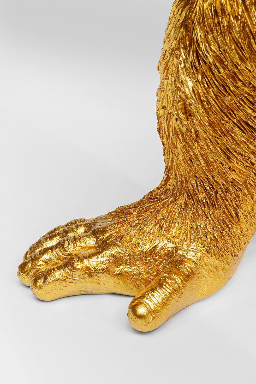 Nahaufnahme einer goldenen Affenpfote von der Deko-Figur Butler Chimp, seitliche Perspektive.