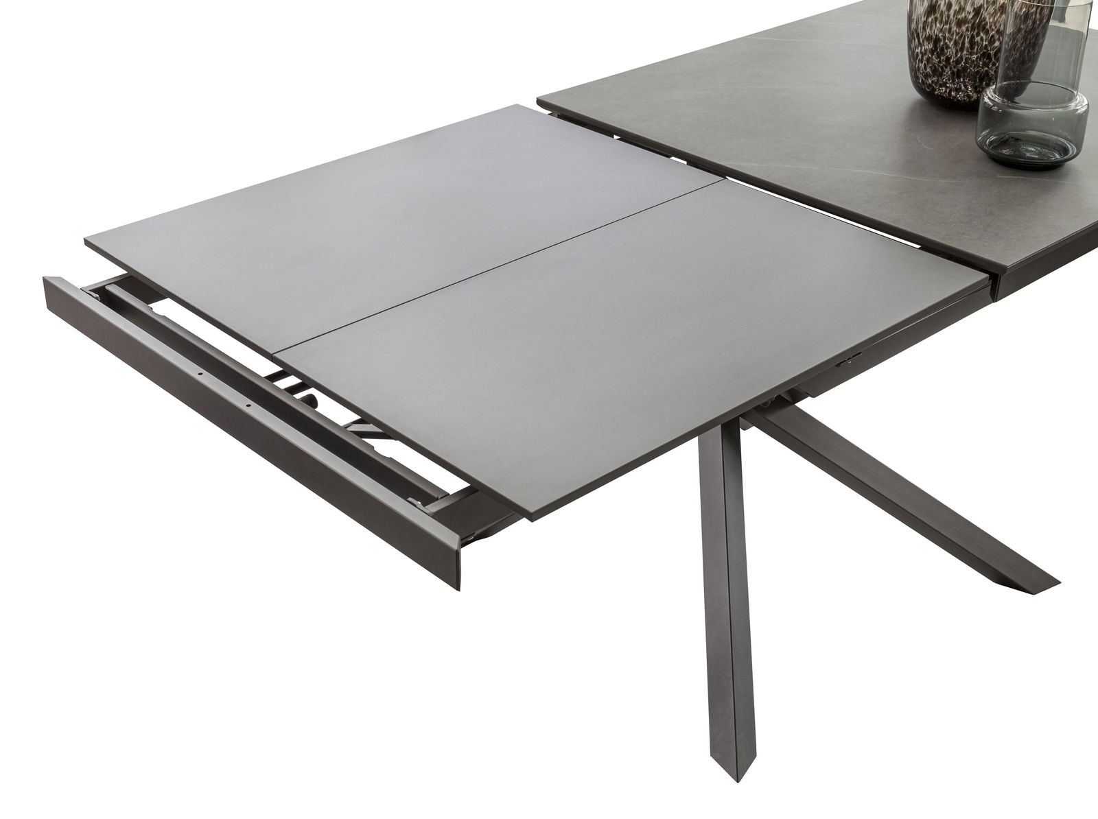 Erweiterbarer Esstisch TOKYO von Zurbrüggen in moderner Perspektive, teilweise ausgezogen mit grauer Tischplatte und stabilen Metallbeinen.