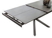 Erweiterbarer Esstisch TOKYO von Zurbrüggen in moderner Perspektive, teilweise ausgezogen mit grauer Tischplatte und stabilen Metallbeinen.