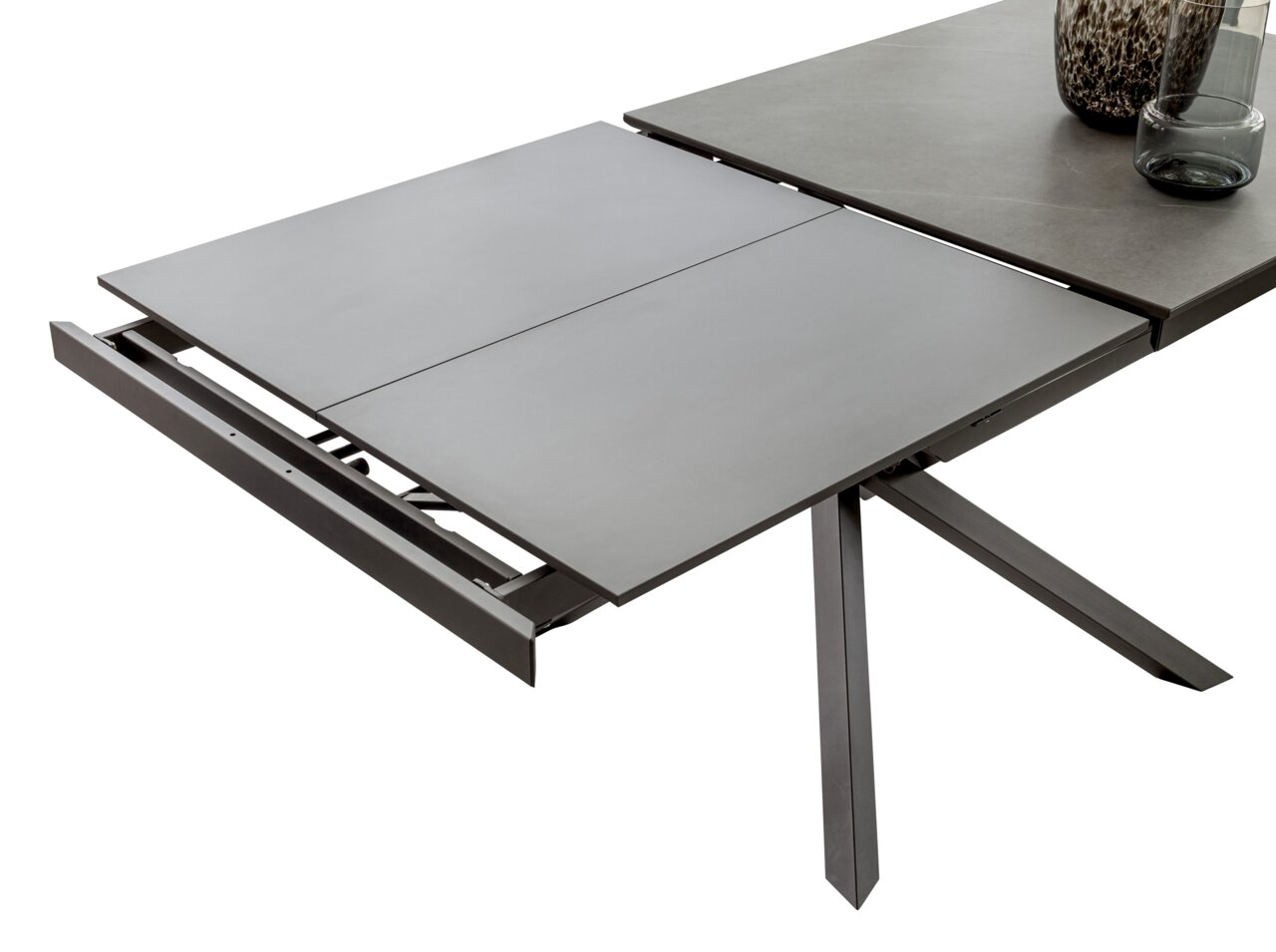 Erweiterbarer Esstisch TOKYO von Zurbrüggen in moderner Perspektive, teilweise ausgezogen mit grauer Tischplatte und stabilen Metallbeinen.