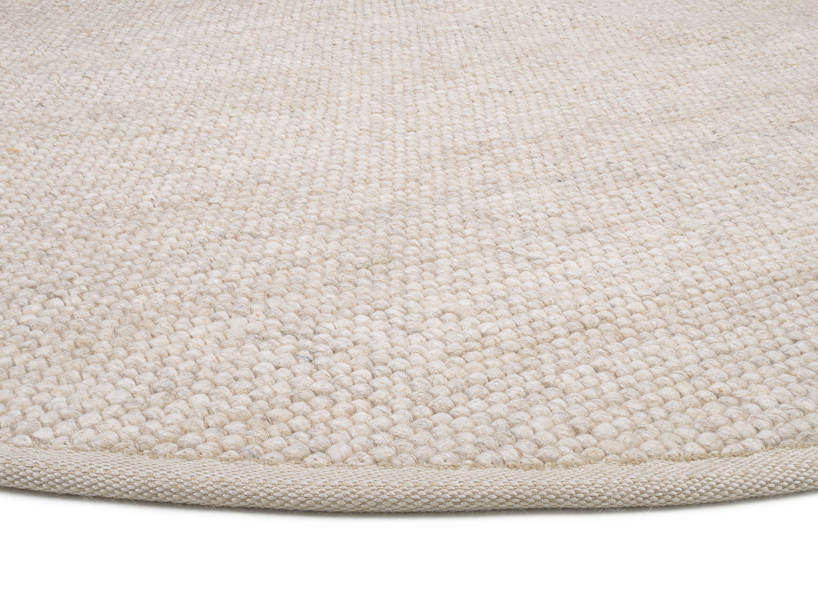 Nahaufnahme eines handgewebten Teppichs in natürlichem Beige, von der Seite fotografiert.