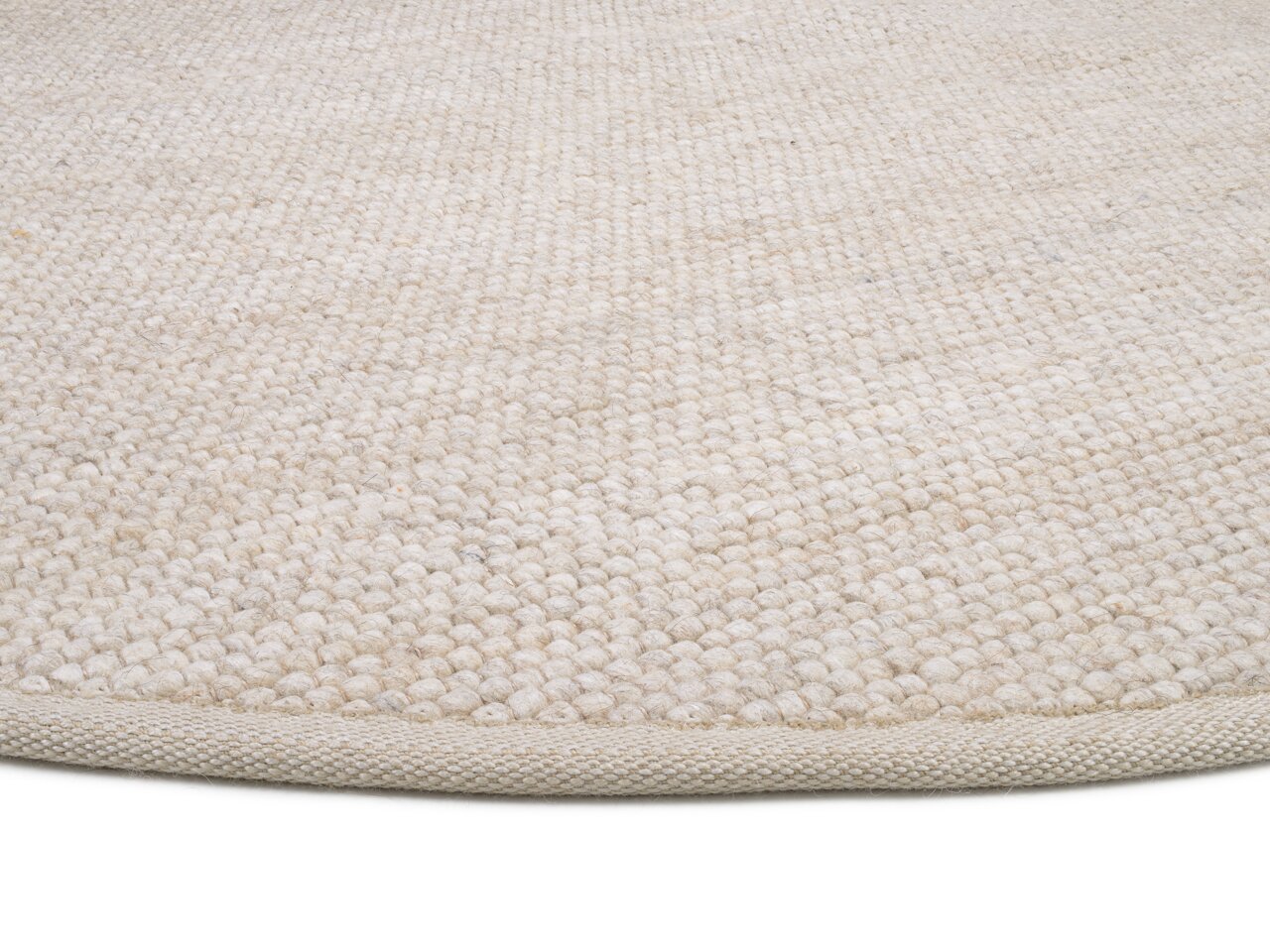 Nahaufnahme eines handgewebten Teppichs in natürlichem Beige, von der Seite fotografiert.