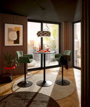 Moderner Barhocker in grünem Stoffbezug mit schwarzem Metallfuß, in einem stilvoll eingerichteten Raum mit Blick auf die Stadt.