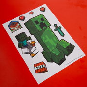 Minecraft Stickerbogen mit Creeper, Zombie auf Huhn, TNT-Block, Pixel-Schwert und Herzen auf rotem Hintergrund, schräg von oben fotografiert