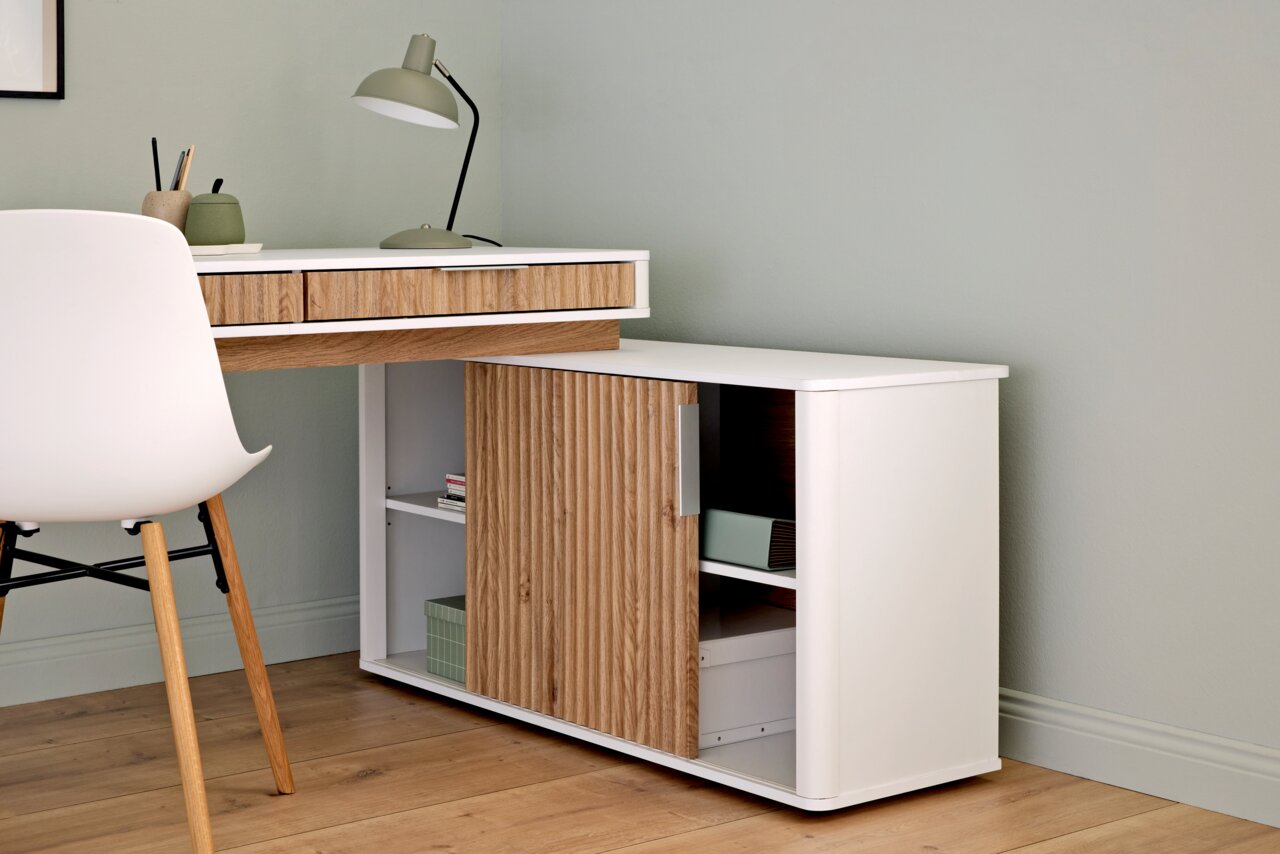 Moderner Eck-Schreibtisch mit Anbau, aus Holz und Weiß, mit Schubladen und Regalfächern, seitliche Perspektive.