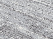 Nahaufnahme eines Uni-Teppichs mit weicher, flauschiger Textur in Grau- und Weißtönen, schräg von oben fotografiert.