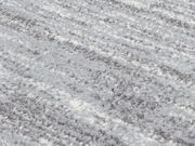 Nahaufnahme eines Uni-Teppichs mit weicher, flauschiger Textur in Grau- und Weißtönen, schräg von oben fotografiert.