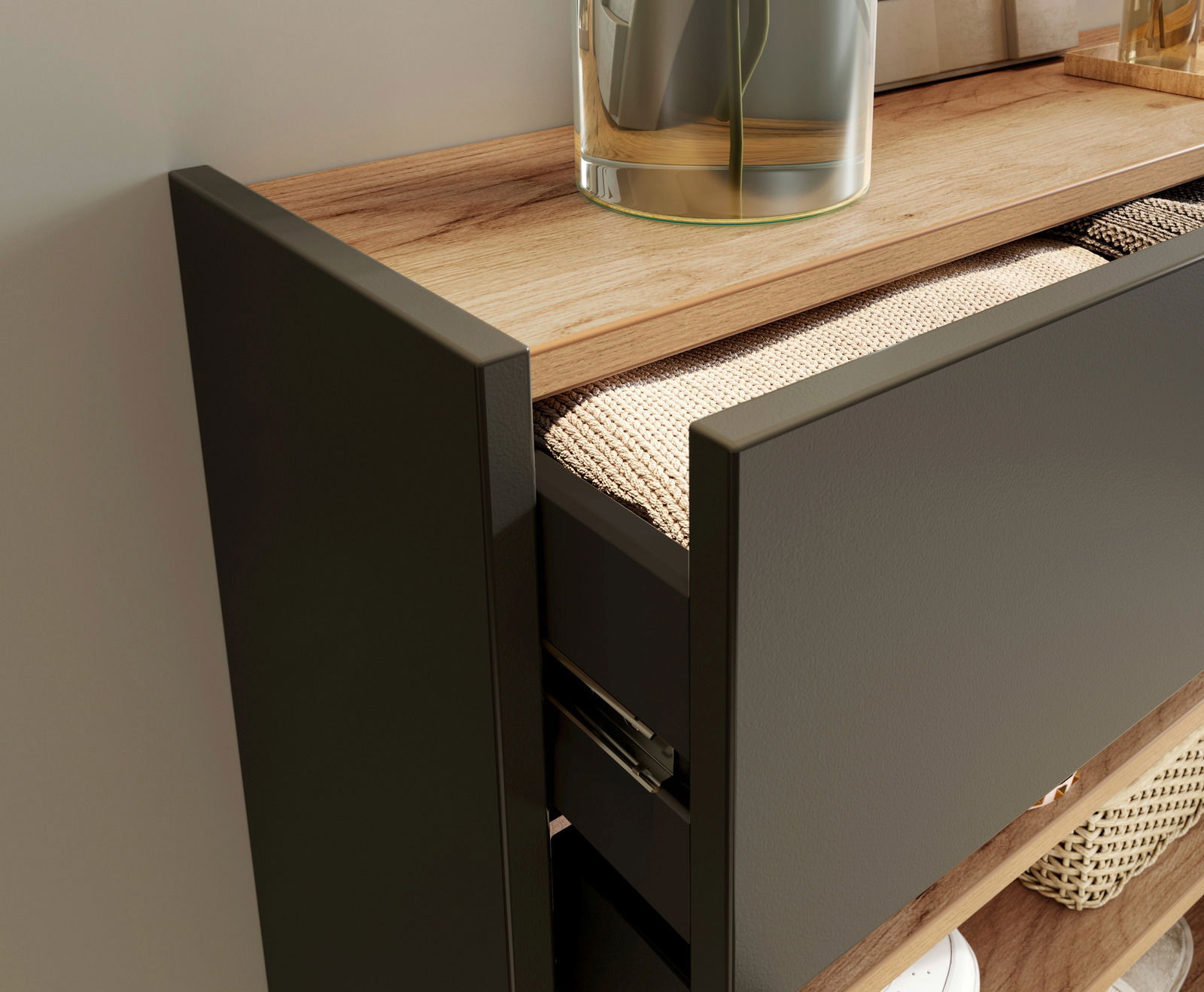 Nahaufnahme eines Hängeschuhschranks mit geöffneter Schublade, die einen geflochtenen Korb zeigt. Die Oberfläche ist aus Holz und darauf steht eine Glasvase. Perspektive von der Seite.