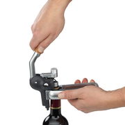 Hebelkorkenzieher von WMF in der Anwendung, seitliche Perspektive auf eine Hand, die den Hebel betätigt, während eine andere Hand die Flasche hält.