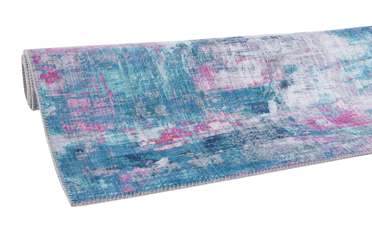 Teppich in Blau- und Pinktönen, teilweise aufgerollt, aus seitlicher Perspektive fotografiert