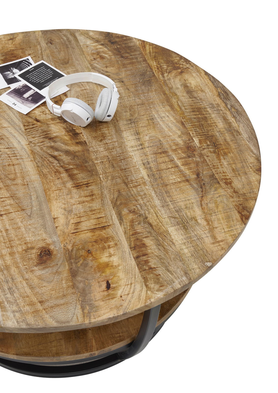 Runder Couchtisch aus Holz mit natürlicher Maserung, von oben fotografiert, mit weißen Kopfhörern und Fotos darauf.