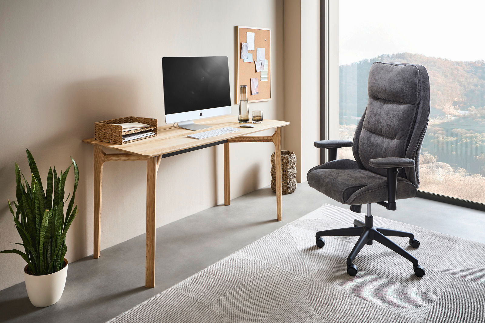 Novel Draaistoel voor thuiskantoor WALTER Moderner Homeoffice-Drehstuhl in Grau, seitliche Perspektive, neben einem Schreibtisch mit Computer und Pflanzen, mit Blick auf eine große Fensterfront.